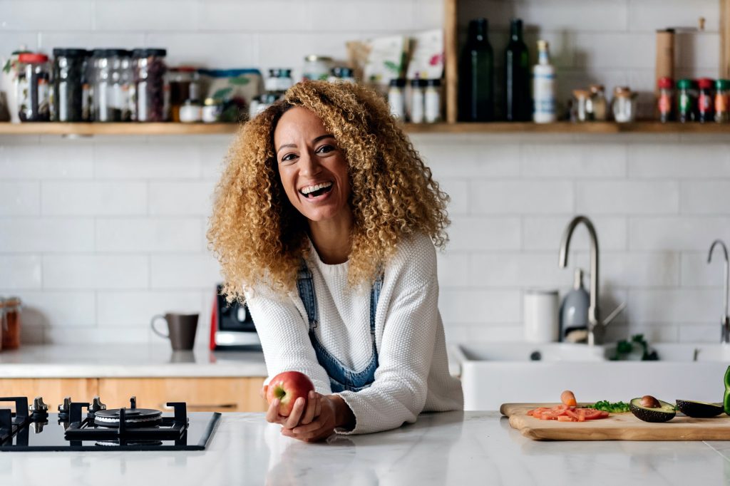 Photo of a smiling woman making a recipe in her kitchen