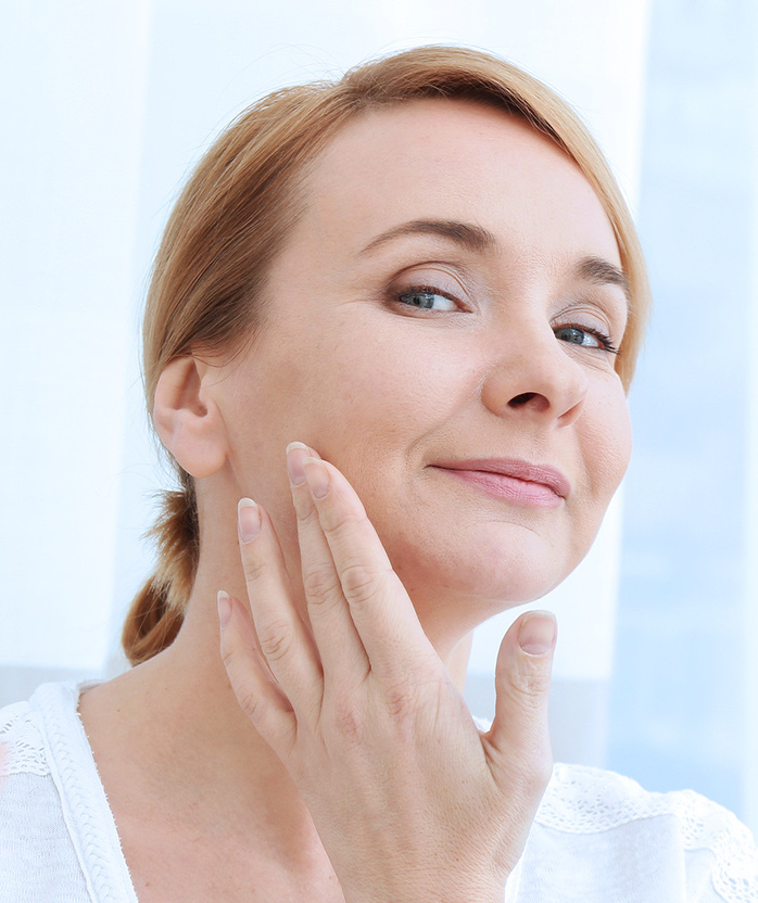 Photo of a middle-aged woman with great skin touching her face