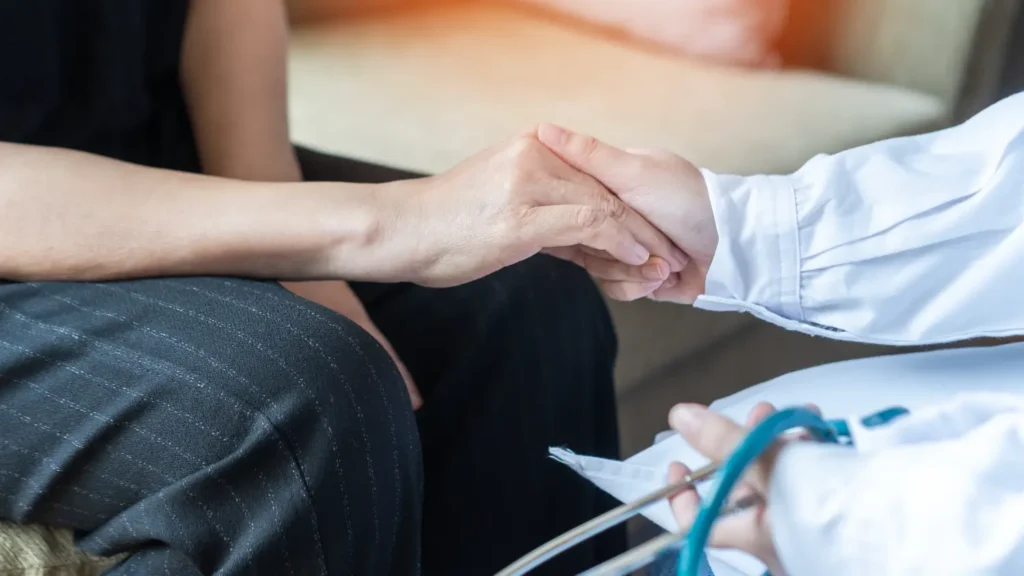 doctor holding a patient's hand during a consultation
