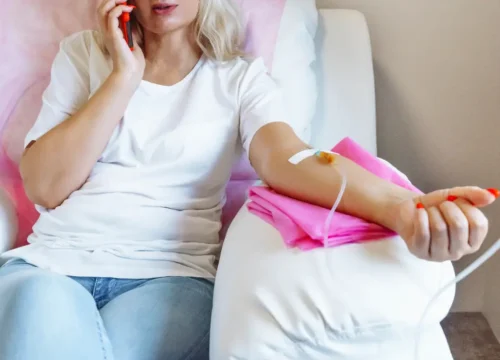woman sitting in a chair with an IV drip in her arm while talking on the phone
