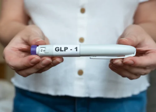 Person holding a GLP-1 labeled injection pen with both hands