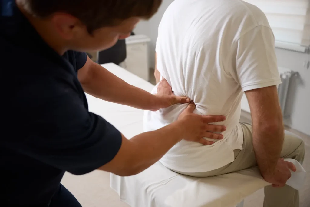 Therapist applying pressure to a patient’s lower back during treatment