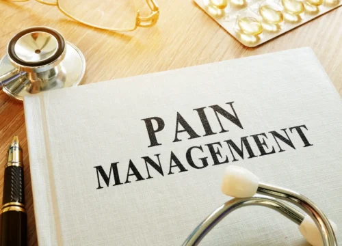 Book labeled pain management with stethoscope and medical items on table