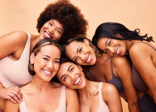 Group of smiling women posing together against a neutral background