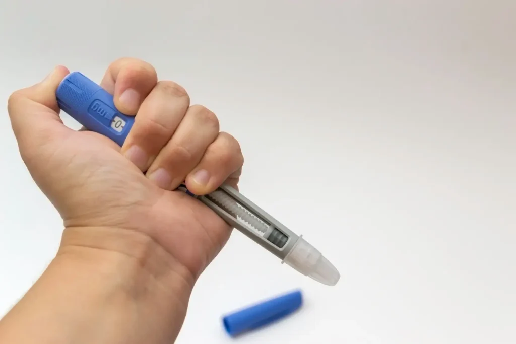 Hand holding a GLP-1 injection pen against a plain background