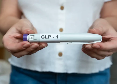 Person holding a GLP-1 medication pen with both hands