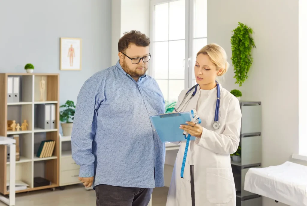 Doctor reviews information on a clipboard with a male patient during a medical consultation.