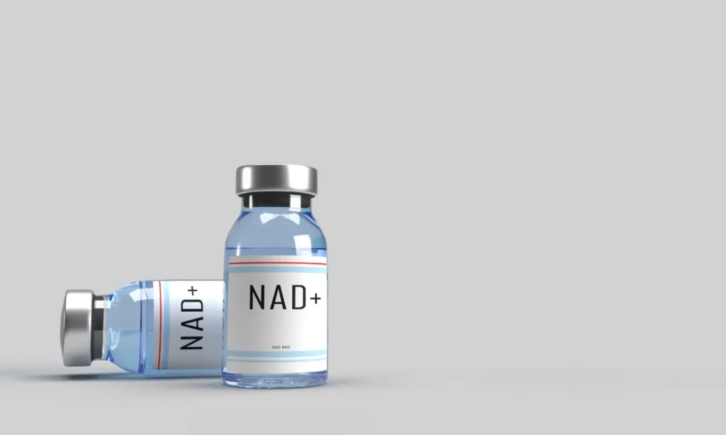 Two vials labeled NAD+, one upright and one lying on its side, against a gray background.